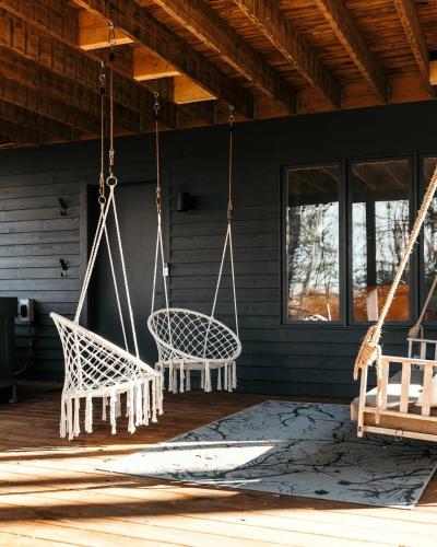 a porch with two swinging chairs and a table at Idyll Reserve - Hocking Hills in South Bloomingville