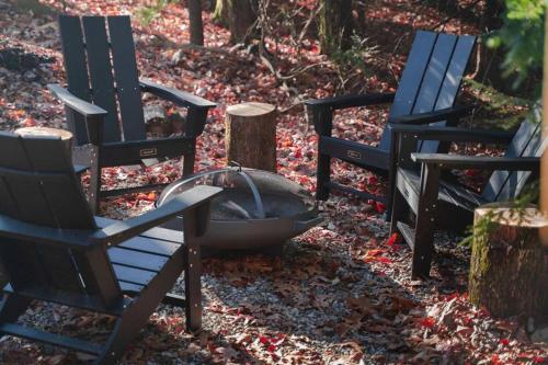 three chairs and a fire pit in the woods at Idyll Reserve - Hocking Hills in South Bloomingville