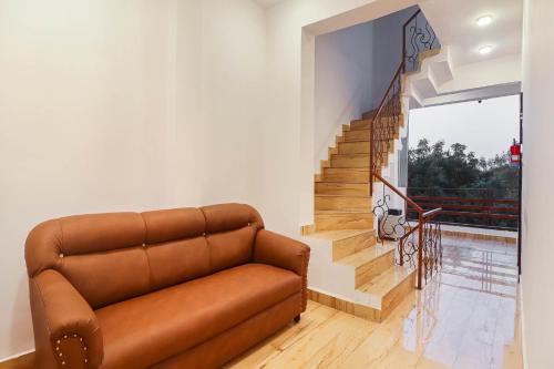 a brown couch in a living room with a staircase at Super HOTEL O CK INN in Charbagh