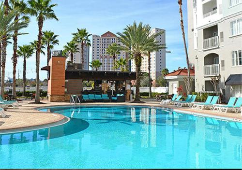 a large swimming pool with chairs and palm trees at The Point Hotel & Suites - 503 Luxury - Pool view - Close to Universal in Orlando