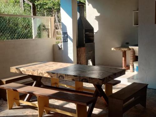 a wooden table and benches in a room with a window at Chácara Sonho Meu Juquitiba SP in Juquitiba