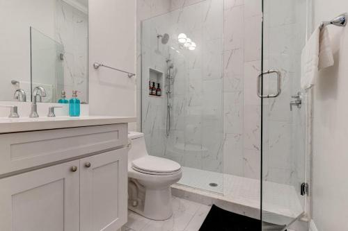 a white bathroom with a shower and a toilet at Mid-City 3BR w Pool Balcony Near Streetcar & FQ in New Orleans