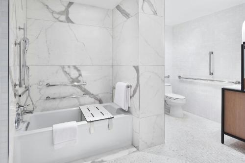 a white bathroom with a tub and a toilet at The Luxury Collection Hotel Manhattan Midtown in New York