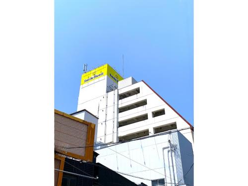 a white building with a yellow sign on top of it at Smile Hotel Nabari - Vacation STAY 70541v in Nabari