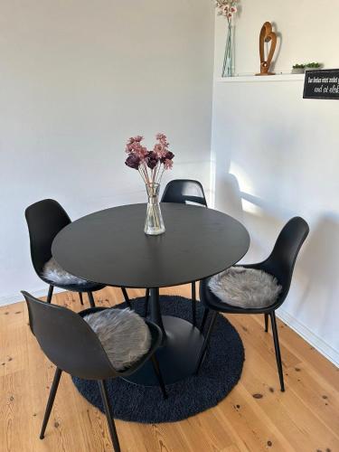 a black table with chairs and a vase of flowers at Mercedes' In in Randers