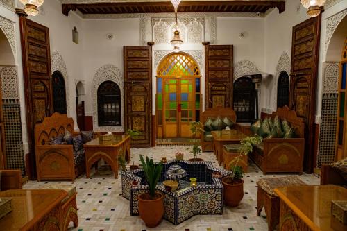 a living room with a large room with tables and chairs at Riad Hikaya - Fes Story in Fès