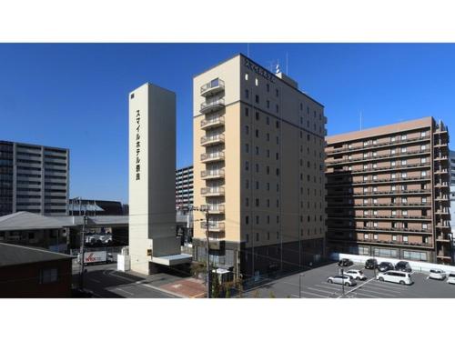 a tall building with cars parked in a parking lot at Smile Hotel Nara - Vacation STAY 73673v in Nara