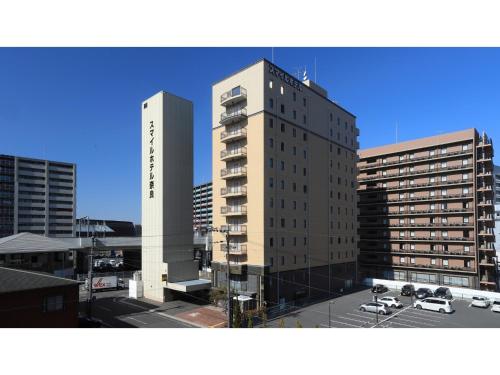 a tall building with cars parked in a parking lot at Smile Hotel Nara - Vacation STAY 73673v in Nara