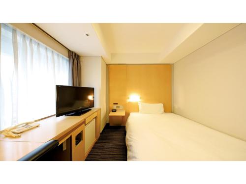 ein Hotelzimmer mit einem Bett und einem Flachbildfernseher in der Unterkunft Smile Hotel Osaka Yotsubashi - Vacation STAY 73524v in Osaka