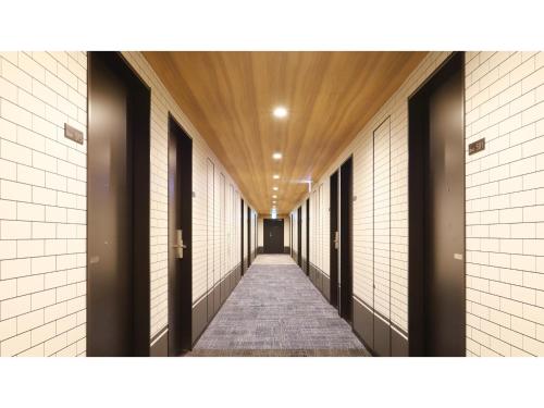 a hallway with white tile walls and a wooden ceiling at Smile Hotel Shonan Fujisawa - Vacation STAY 74519v in Fujisawa