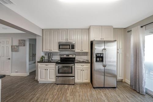 a kitchen with white cabinets and a stainless steel refrigerator at Waterfront Retreat Home Dania Beach in Dania Beach