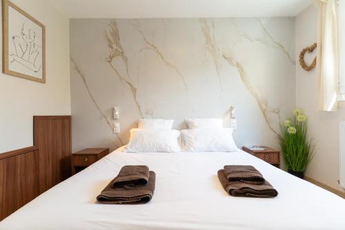 une chambre avec un lit blanc avec des serviettes dessus dans l'établissement Les Sorbiers & spa, à Saint-Avertin