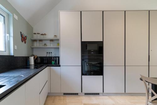 une cuisine avec des armoires blanches et des comptoirs noirs dans l'établissement Les Sorbiers & spa, à Saint-Avertin