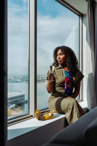 a woman sitting on a window sill drinking a glass of wine at Renaissance Boston Seaport District in Boston