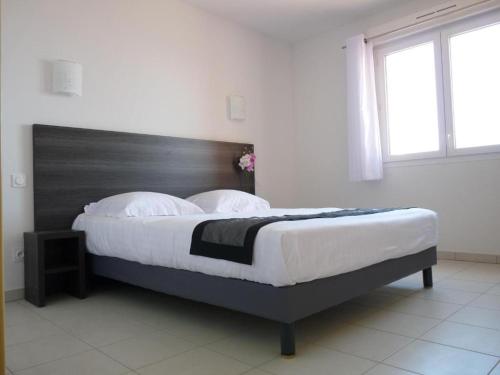 a bedroom with a large bed with a wooden headboard at Appart'hotel Résidence La Provence in Istres