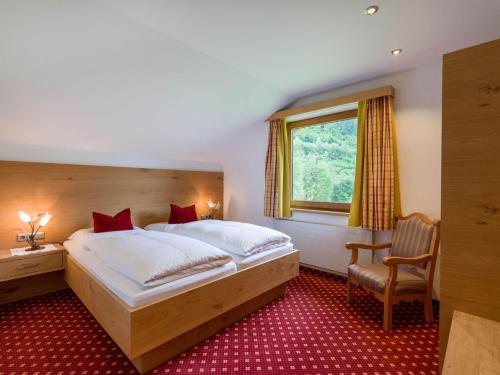 a bedroom with a bed and a chair and a window at Ferienhof Oblasser in Mayrhofen