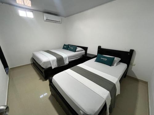 two beds in a small room with white walls at Hotel Marlon in Villavicencio
