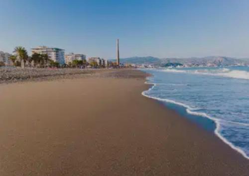 une plage avec l'océan et des bâtiments en arrière-plan dans l'établissement Amplio apartamento, playa, tren, à Malaga