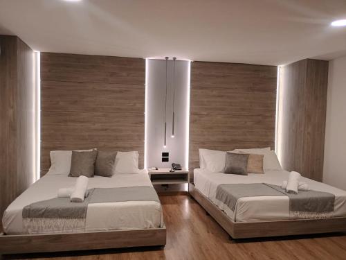 two beds in a bedroom with wooden floors at Hotel Time Oclock in Medellín