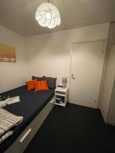 a room with a bed and a door with orange pillows at Independent Cozy apartment in husby in Stockholm