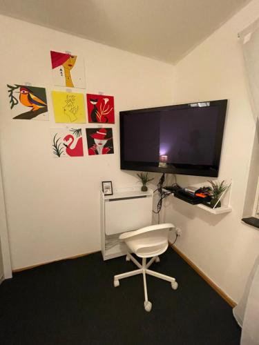 a room with a white chair and a flat screen tv at Independent Cozy apartment in husby in Stockholm