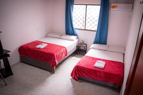 a bedroom with two beds with red sheets and a window at Casa Salmón Confortable Casa Completa Valledupar in Valledupar