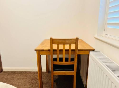 a wooden table with a wooden chair sitting at it at Budget Stay In Luton 01 R in Luton