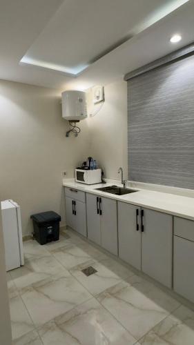 a kitchen with white cabinets and a sink and a window at Studio with a calm and comfortable designse in Al ‘Awālī