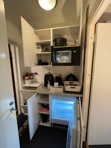 a small kitchen with white cabinets and appliances at Independent Cozy apartment in husby in Stockholm