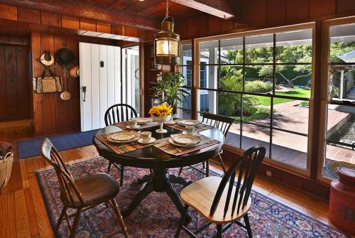 a dining room with a table and chairs and a large window at Rincon Retreat by Paradise Retreats in Carpinteria