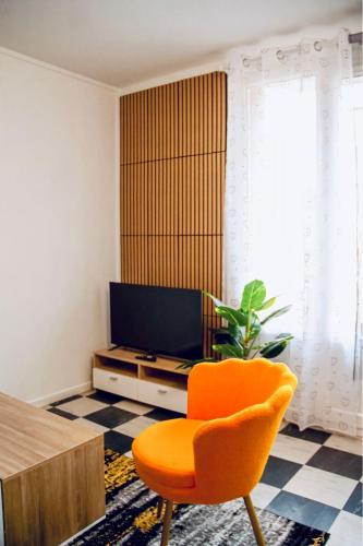 an orange chair in a living room with a television at T3 spacieux et lumineux in Châteauroux