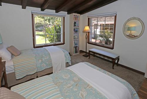 a bedroom with two beds and a mirror at Rincon Retreat by Paradise Retreats in Carpinteria
