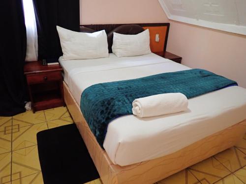 a bedroom with a large bed with a green blanket at Sunset Junction Lodge & Tours in Livingstone