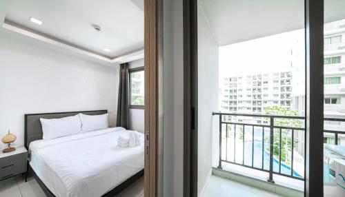 Un dormitorio con una cama y un balcón. en Arcadia Beach 芭提雅市中心公寓, en Pattaya South