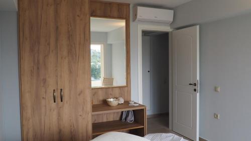 a bedroom with a wooden cabinet with a mirror at The Lakehouse in Vouliagmeni Lake