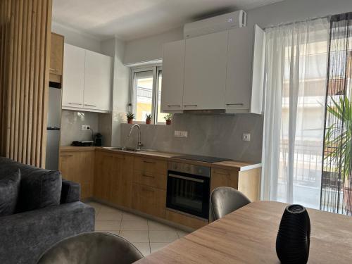 a kitchen with white cabinets and a table and a couch at Salt & Soul downtown apartment in Mesolongion