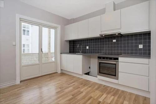 a kitchen with white cabinets and a wooden floor at Tønsberg centrum in Tønsberg