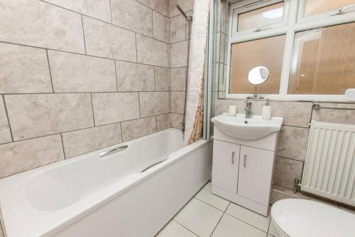 a bathroom with a tub and a sink and a toilet at Coal Miners Cottage - Moments To Seafront & Town in Deal