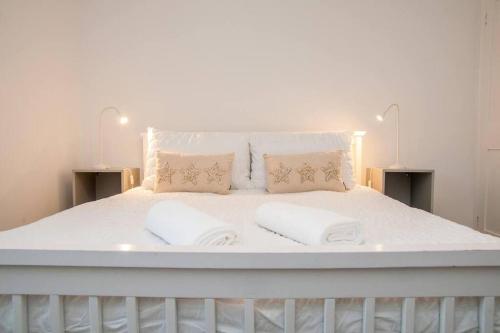 a large white bed with two pillows on it at Coal Miners Cottage - Moments To Seafront & Town in Deal