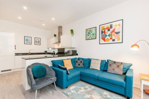 a living room with a blue couch and a kitchen at Ground Floor Garden Apartment Walpole Bay Margate in Margate