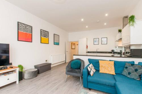 a living room with a blue couch and a kitchen at Ground Floor Garden Apartment Walpole Bay Margate in Margate