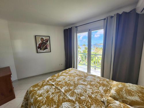 a bedroom with a bed and a large window at Tartane - T3 - L'interlude à l'Anse Rouge in La Trinité