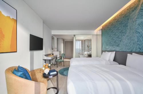 a hotel room with two beds and a table at voco Ma Belle Danang by IHG in Da Nang