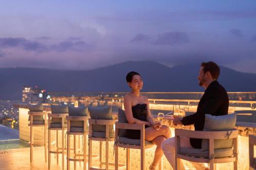 a man and a woman sitting at a table on a roof at voco Ma Belle Danang by IHG in Da Nang