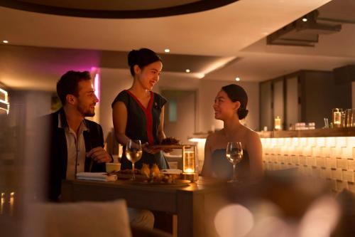 a group of people standing around a table in a restaurant at voco Ma Belle Danang by IHG in Da Nang