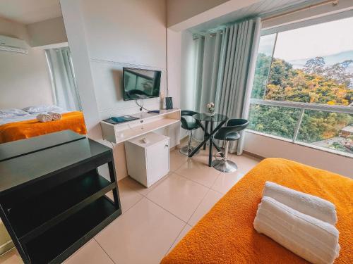 a room with two beds and a desk and a television at Loft vista panorâmica da Roda gigante e orla de BC in Balneário Camboriú