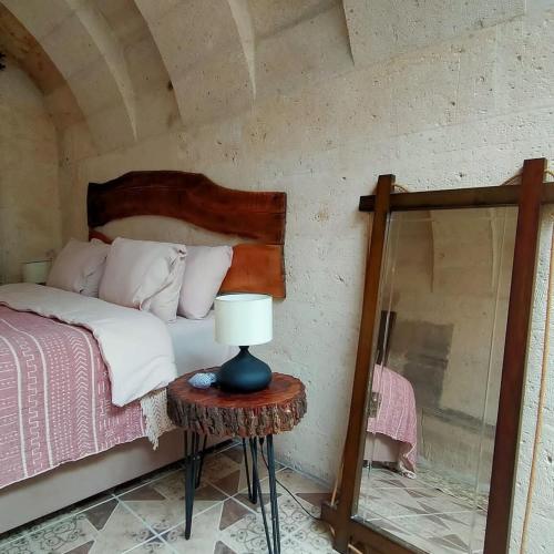 a bedroom with a bed and a table with a lamp at DEEP CAVE House in Urgup