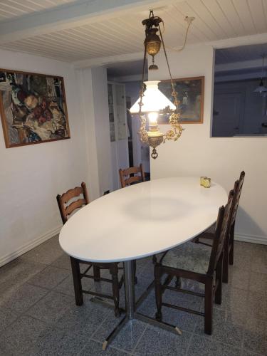 a white dining room table with chairs and a chandelier at Lejbølle Gamle Bageri in Tranekær