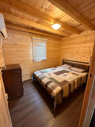 a bedroom with a bed in a wooden cabin at The Pines Cottage on the Lake in Otter Lake