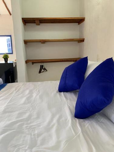a bed with blue pillows on top of it at Refugio en Barichara con piscina, jardines y atardeceres únicos in Barichara